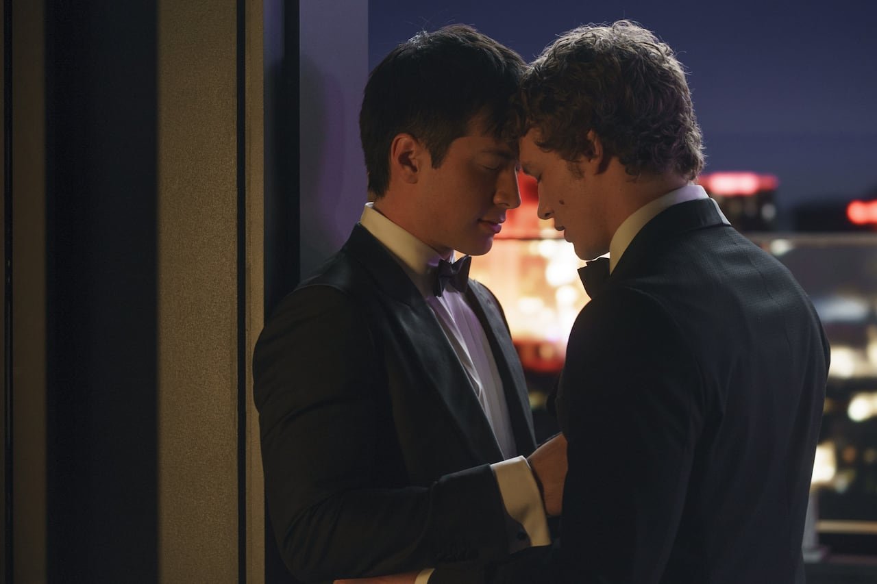 default-1293 Two men in formal attire leaning heads against each other on a rooftop.