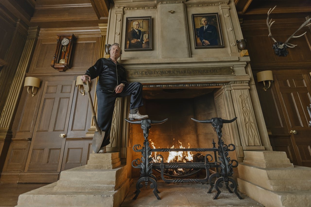 A man stands on an ornate mantel while holding a shovel